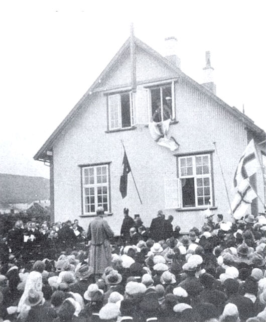 Páll Patursson heingir føroyska Merkið út av vindeyganum (Mynd: A. Rasmussen - Úr Flaggsøguni hjá Niels Juel Arge)